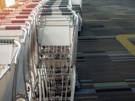 Airport luggage cart in airport near the glass window.