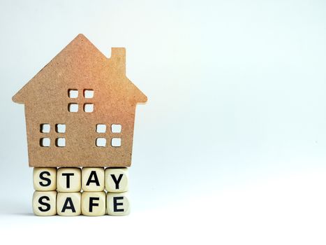 Stay safe concept. Word "Stay Safe" with wooden house isolated on white background with copy space, stay at home, social media campaign for covid-19 or coronavirus pandemic prevention.