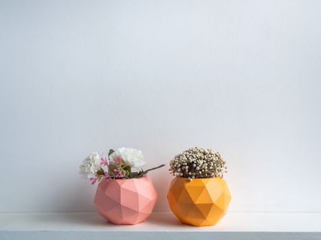 Cactus pot. Concrete pot. Pink and orange modern geometric concrete planters with blooming flower on white wooden shelf isolated on white background.