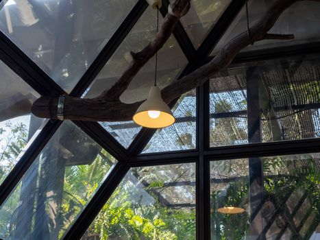 Modern ceiling light or light bulb hanging from ceiling in glass house construction building. Retro lighting decoration.