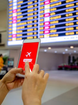 Flight check-in by mobile phone. Hand touching on smartphone screen to check-in for a flight in terminal airport verticals tyle.