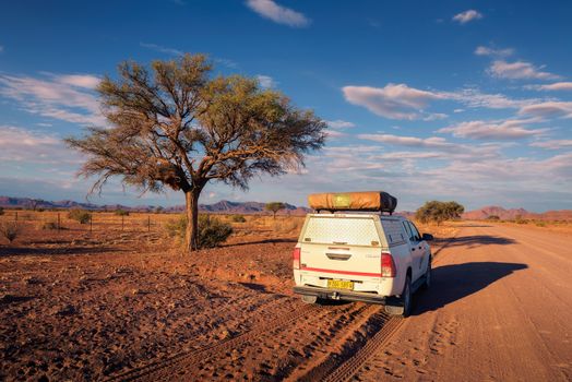 Karas, Namibia - March 30, 2019: Typical 4x4 rental car in Namibia equipped with camping gear and a roof tent driving on a dirt road through Karas Region in Namibia.