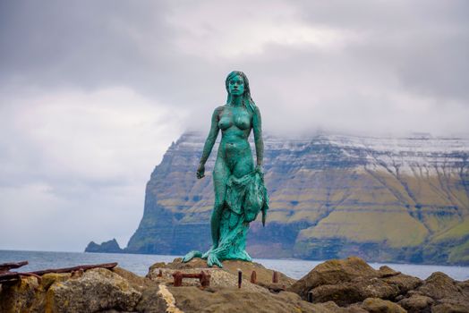 Mikladalur, Faroe Islands, Denmark - May 27, 2019 : Statue of Selkie or Seal Wife in Mikladalur on the island of Kalsoy. Selkies are mythological creatures in Irish, Scottish, and Faroese folklore.