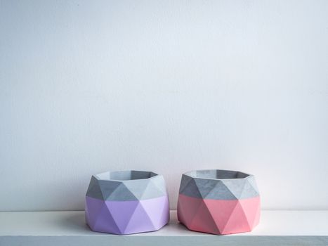 Cactus pot. Concrete pot. Two empty pink and purple modern geometric concrete planters on white wooden shelf isolated on white background.