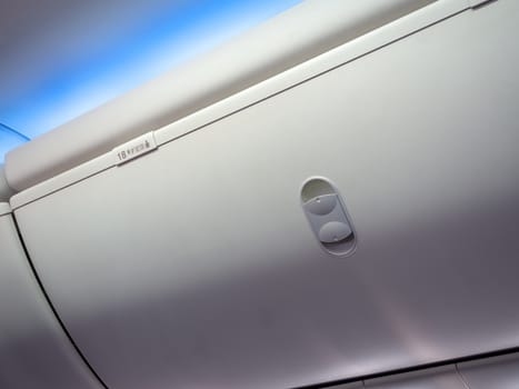 Close-up hand luggage compartment in cabin economy class on the low cost commercial airplane.