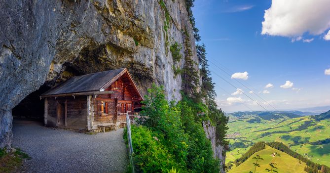 Ebenalp, Switzerland - July 18, 2019 : Historic wooden cabin built in the Wildkirchli cave with panoramic views over the valley in the Appenzell region of Switzerland.