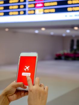 Flight check-in by mobile phone. Hand touching on smartphone screen to check-in for a flight in terminal airport vertical style.