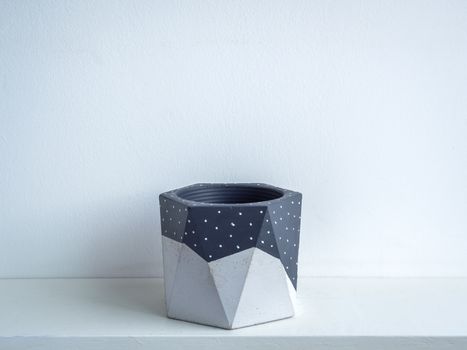 Cactus pot. Concrete pot. Empty grey painted modern geometric concrete planter on white wooden shelf isolated on white background.