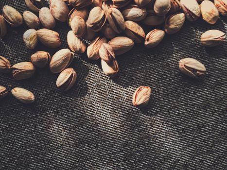 Pistachio nuts on rustic linen background, food and nutrition