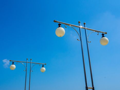 Street lights on steel poles on blue sky background.