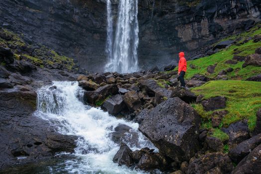 Tourist standing at the Fossa Waterfall on island Bordoy in the Faroe Islands, Denmark