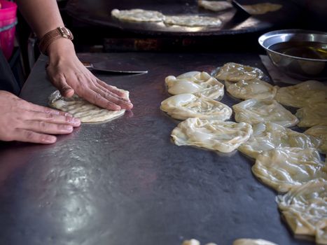 Roti Making, roti thresh flour by roti maker with oil. Indian traditional street food. Hand making roti.