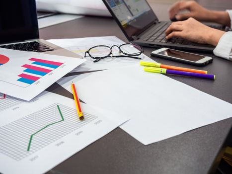 Business goal concept. Business accessory, blank paper, diagrams graphs, smartphone, pencil, glasses, highlighter pen with hands working with laptop computer on table.