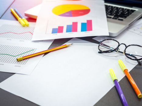 Business goal concept. Business accessory, blank paper, diagrams graphs, pencil, laptop computer, glasses and highlighter pen on table.