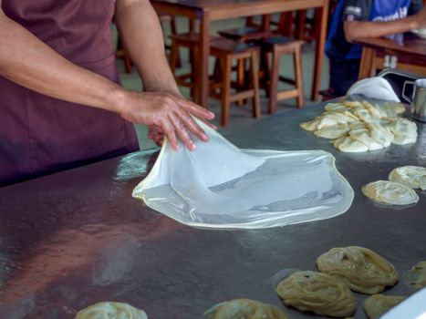 Roti Making, roti thresh flour by roti maker with oil. Indian traditional street food. Hand making roti.