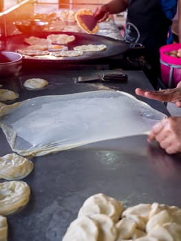 Roti Making, roti thresh flour by roti maker with oil. Indian traditional street food. Hand making roti vertical style.