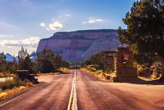 Zion National Park, Utah, USA - October 21, 2018 : Road and welcome sign at the entrance to Zion National Park before sunset.