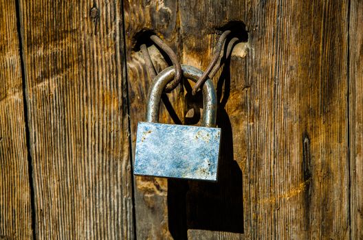 Rusty padlock on an old and deteriorated door