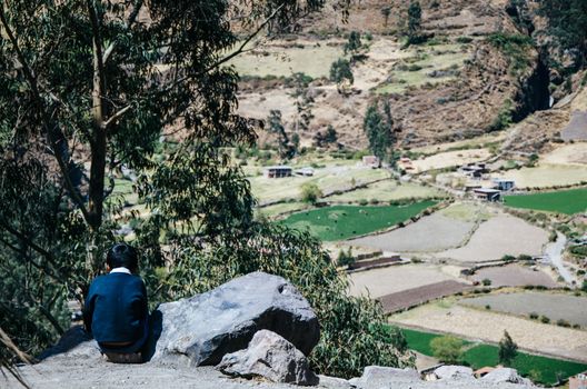 Child sitting on his back on the top of a mountain