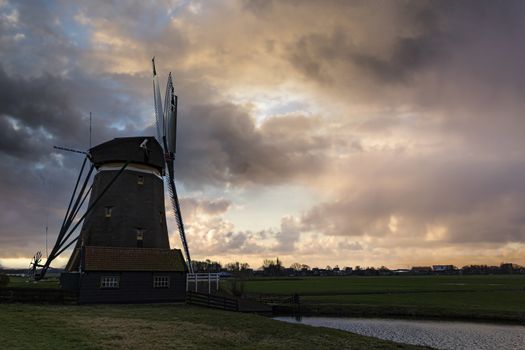 Dutch windmill facing the early rain winds and running the turbine to pump the water out from the lands