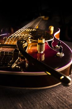 Closeup of sunburst electric guitar with brass mechanics and bright colors on a dark shaded background