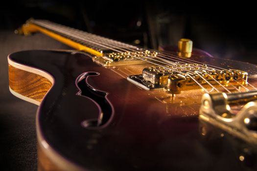 Closeup of sunburst electric guitar with brass mechanics and bright colors on a dark shaded background