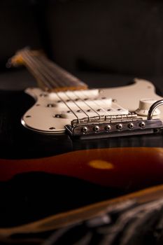 Close-up of a sunburst-colored electric guitar covered with black paint removed at certain points to create the worn out effect