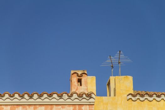 Yellow sea house roof with tiles, fireplace and television anten