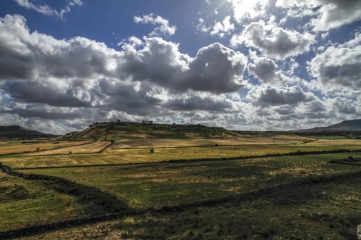 Clear sky with natural colors of an intense Mediterranean blue and white clouds on a plain of typical Sardinian vegetation