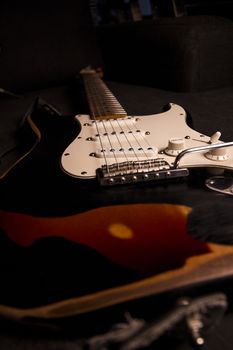 Close-up of a sunburst-colored electric guitar covered with black paint removed at certain points to create the worn out effect