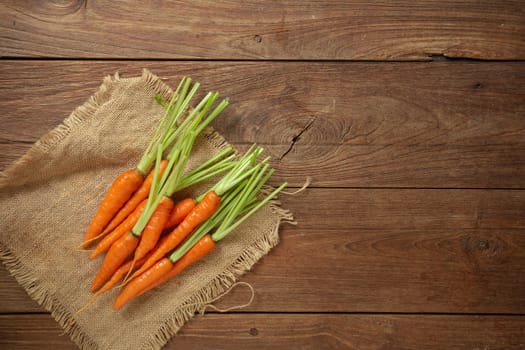 Fresh baby carrots on wooden cutting board and wooden background.