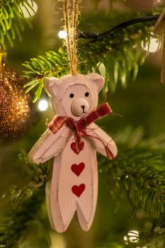 A white wooden bear shaped Christmas Tree Decoration hanging from a tree