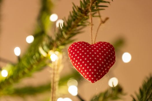 A fabric heart shaped Christmas Tree Decoration hanging from a tree