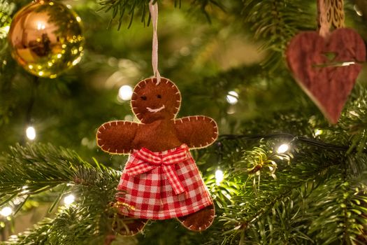 A fabric gingerbread man woman bear shaped Christmas Tree Decoration hanging from a tree