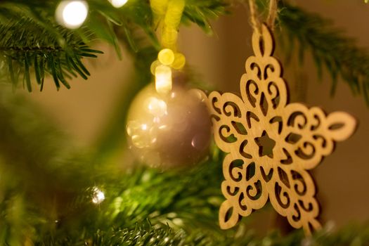 A wooden star shaped Christmas Tree Decoration hanging from a tree