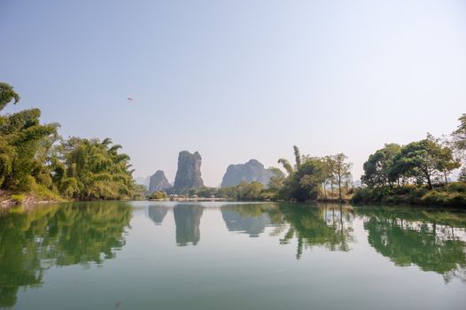 Lake with limestone karst hills foggy landscape reflecting in the river in Yangshuo, Guangxi province, China