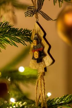 A wooden tree shaped Christmas Tree Decoration hanging from a tree