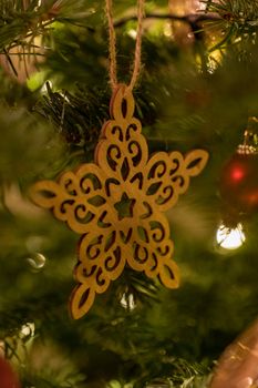 A wooden star shaped Christmas Tree Decoration hanging from a tree