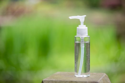 Hand sanitizer container against out of focus green vegetation