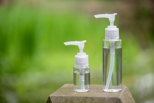 Two hand sanitizer containers against out of focus green vegetation