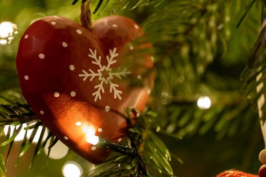 A red wooden heart shaped Christmas Tree Decoration hanging from a tree