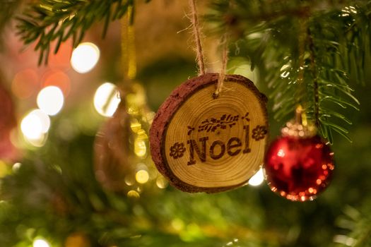 A Noel log shaped Christmas Tree Decoration hanging from a tree