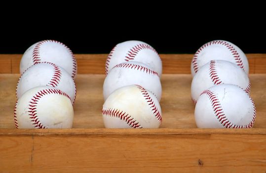 A wooden tray with nine baseballs at a throwing game
