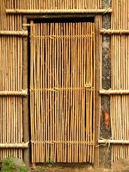 A handmade bamboo door leading to a native dwelling
