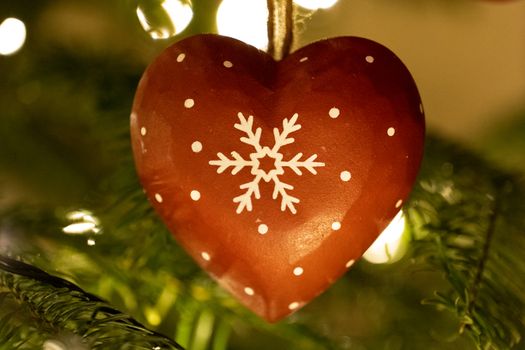 A red wooden heart shaped Christmas Tree Decoration hanging from a tree