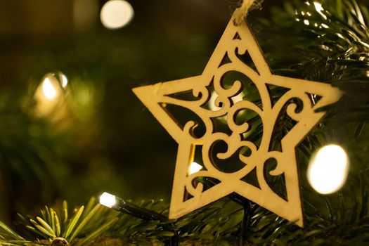A wooden star shaped Christmas Tree Decoration hanging from a tree