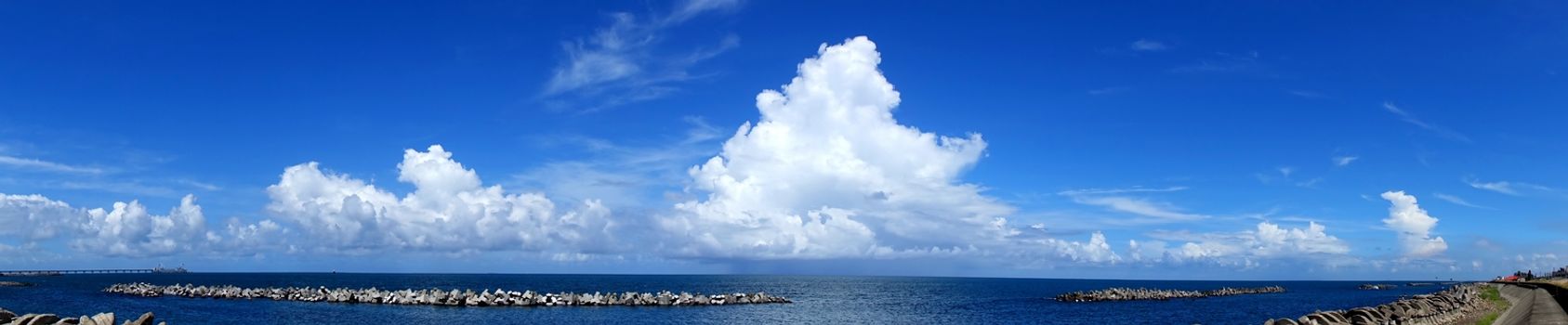 Beautiful panorama of ocean and sky and clouds with concrete breakwaters