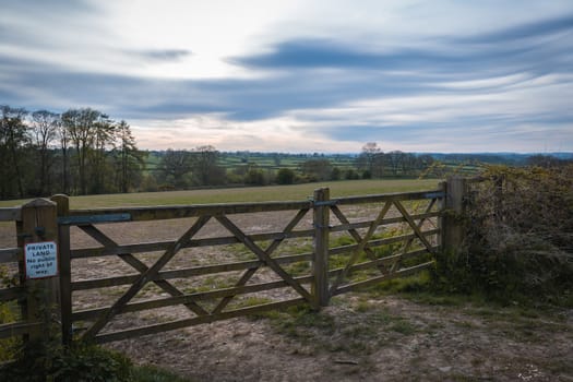 An old rustic wooden farm gate and a beautiful countryside landscape and colorful sky