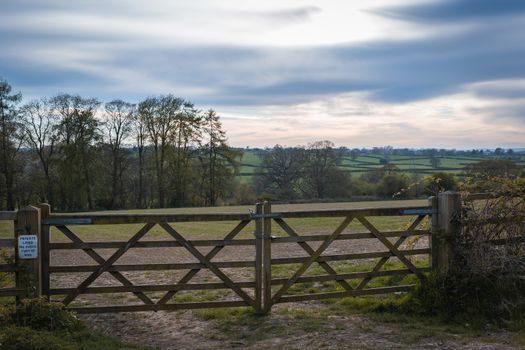 An old rustic wooden farm gate and a beautiful countryside landscape and colorful sky
