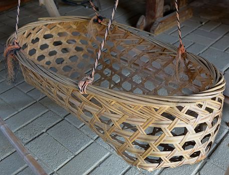 An old infant crib suspended by ropes and made from bamboo strips